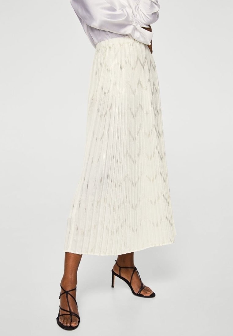 Jupe midi plissée de couleur blanc cassé avec un motif en losange subtil, confectionnée dans un tissu léger. Accompagnée de sandales à talons noires.