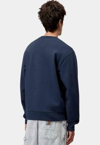 Sudadera de cuello redondo en color navy, fabricada en algodón, con un corte holgado, puños acanalados y un dobladillo limpio. Textura suave sin patrones visibles.