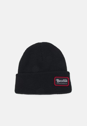 Bonnet tricoté noir avec un revers. Présente un patch rectangulaire blanc et rouge sur le côté. Motif texturé sur tout le tissu.