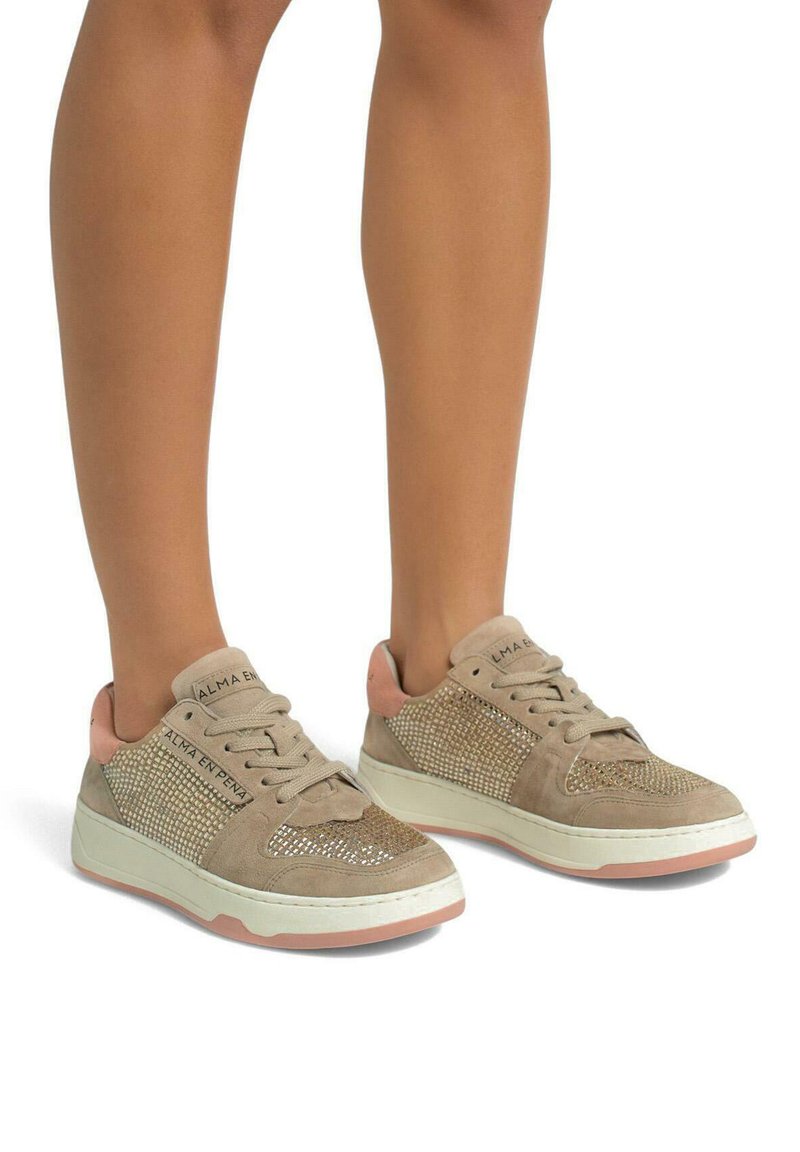 Beige suede sneakers with sparkling accents, featuring a textured upper, lace-up design, and a light pink heel cap. White and pink sole.