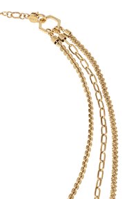 Guldfärgat halsband med tre kedjor: en slät, en med förlängda länkar och en texturerad kedja. Säkerställs med ett sexhörnat lås.