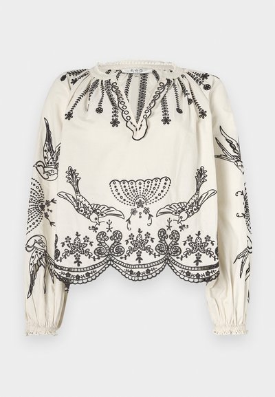 White blouse with black embroidered floral and bird patterns. Features a scalloped hem, puffed sleeves, and a round neckline with detailing.
