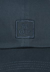 Dark blue cap made of woven fabric, featuring an embroidered logo "M O’P" within a rectangle on the front. Visible stitching detail.