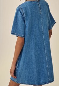Robe en denim à manches courtes, décolleté rond et fermeture arrière à boutons. Présente une coupe décontractée et un lavage bleu avec des coutures visibles.