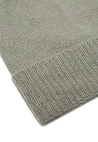 Gorro de lana gris claro de punto con puño acanalado doblado, mostrando textura y detalles de costura sobre un fondo blanco.