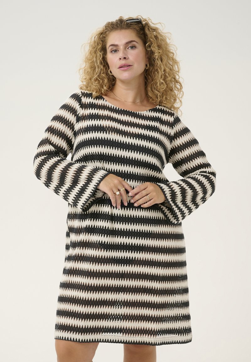 Abito lavorato a maglia con motivo a zigzag nei colori nero, crema e ruggine. Il design ha una vestibilità rilassata con maniche lunghe a campana svasate.