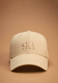 Beżowa czapka bejsbolowa z haftowanym wzorem "93B" z przodu, wykonana z miękkiego materiału, z wygiętym daszkiem i detalami w postaci ściegów.