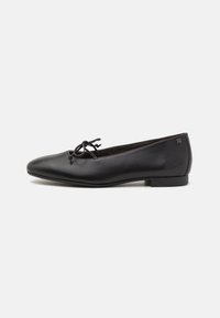 Le ballerine in pelle nera presentano una punta arrotondata, un fiocco decorativo sulla tomaia e un tacco basso e piatto con un sottile dettaglio del logo.