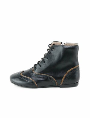 Botín de cuero negro hasta el tobillo con punta redonda, costuras beige y perforaciones decorativas; cuenta con un diseño de cordones y un tacón bajo y plano.