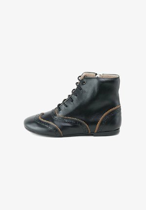 Botín de cuero negro hasta el tobillo con punta redonda, costuras beige y perforaciones decorativas; cuenta con un diseño de cordones y un tacón bajo y plano.