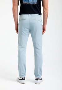 Svetlo modri hlače iz lahkega materiala s slim fit krojem in dvema zadnjima žepoma. V kombinaciji z belimi superge s črnimi detajli.