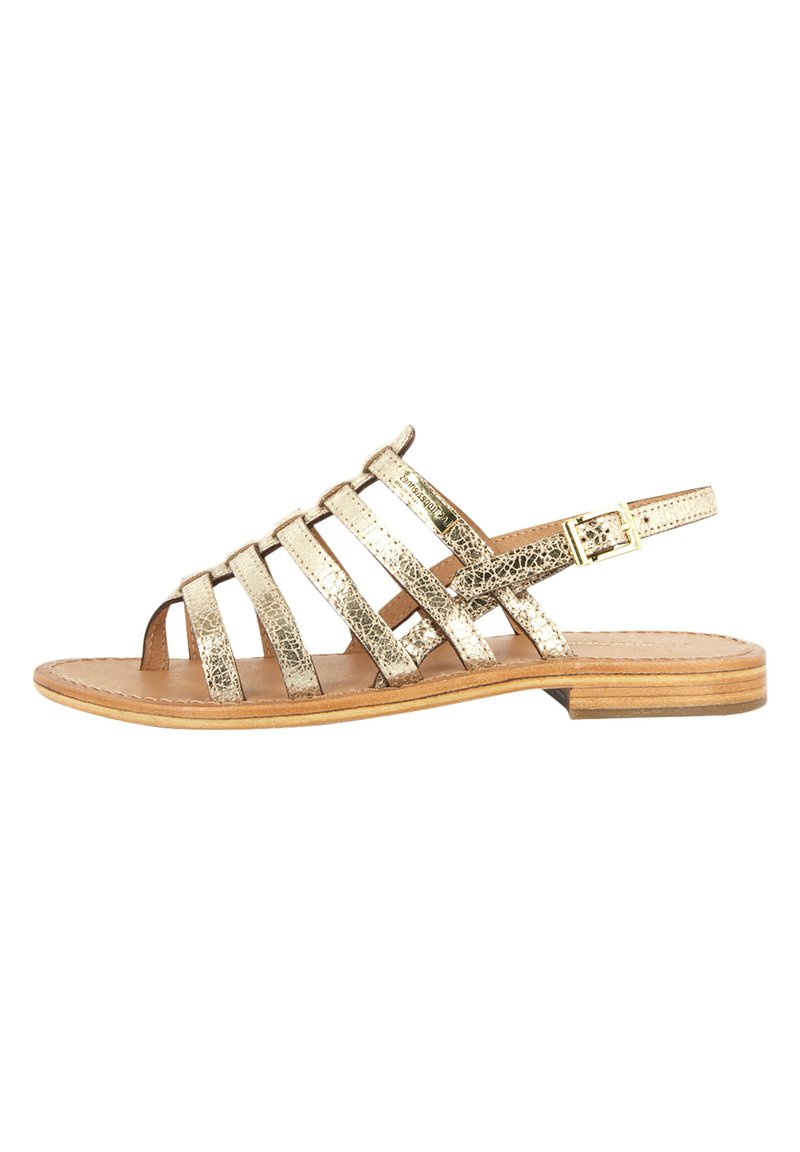 Gouden metallic sandaaltjes met een platte zool, verstelbare gesp en open te ontwerp. Getextureerde bovenkant met een geometrisch kruispatroon.