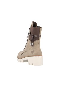 Bottine beige avec un panneau en maille texturé, des lacets gris et une semelle blanche épaisse. Présente un détail de logo sur le côté et un matériau durable.