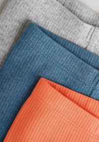 Drie paar ribbels leggings in grijs, blauw en oranje, met een gestructureerde stof en elastische taillebanden.
