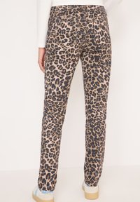 Kalhoty s leopardím potiskem v béžové a černé barvě, vybavené pěti kapsami a slim fit designem. Tkanina má mírnou strukturu s jemným povrchem.