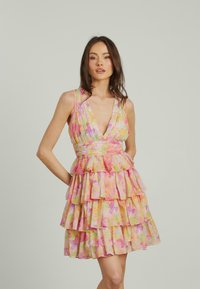 Blumenmuster-Kleid mit tiefem V-Ausschnitt, gestuften Rüschen und taillierter Passform. Die Farben umfassen Pink, Gelb und Grün, gefertigt aus leichtem Stoff.