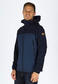Mørkeblå zip-up jakke med hætte, der har et mørkeblåt panel, sidelommer med lynlås, elastiske manchetter og en struktureret stoffinish.