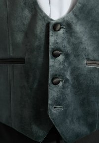 Dunkelgrüne Weste aus weichem, wildlederähnlichem Material, mit drei runden schwarzen Knöpfen und einem eleganten schwarzen Besatz entlang des Taillenbereichs.