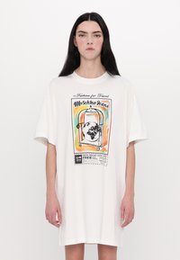 Hvitt oversized t-skjorte med grafisk trykk med fargerikt reise-tema design, rund hals, og korte ermer.