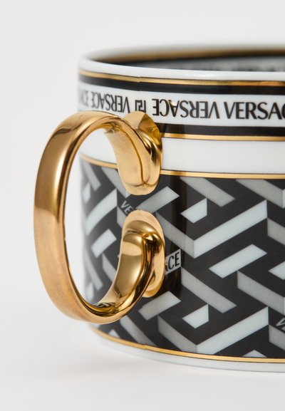 Ceramiczny kubek z czarno-białym geometrycznym wzorem, złotym uchwytem i logo Versace na obrzeżu. Klasyczny design z połyskującym wykończeniem.