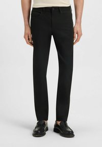 Black trousers made of cotton blend, slim fit, with front and back pockets, metal button closure, and belt loops. Smooth texture.