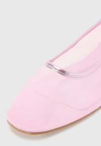 Ballet flat rosa com um upper transparente e texturizado, com uma borda prateada metálica ao longo da abertura e uma sola leve e flexível.
