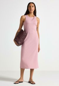 Roserød ribbet midi kjole med ærmeløs design, rund halsudskæring og en lige silhuet, parret med en mørk bordeaux taske og sorte sandaler.
