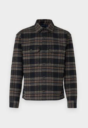 Veste à carreaux noire et grise avec un col, fermeture à boutons et deux poches poitrine. Fabriquée à partir d'un tissu texturé.