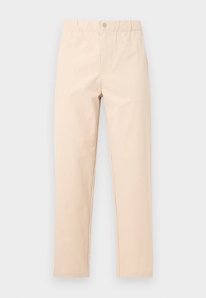 Pantalon beige à jambes droites avec taille élastique et fermeture à bouton, présenté sur un fond gris clair.