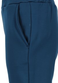 Blauwe sportbroek van een gladde, gestructureerde stof. Voorzien van een zijzak en een elastische tailleband voor een comfortabele pasvorm.