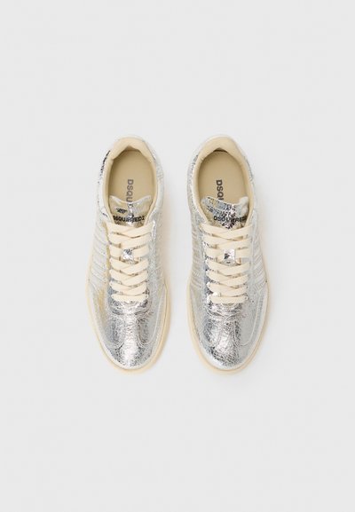 Silver metallic sneakers with a textured surface, cream laces, and subtle logo detail on the tongue. Designed with a rounded toe and a contrasting sole.