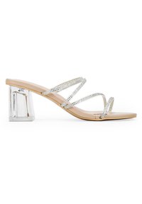Chanclas nude con tacón bloque transparente, que presentan tres tiras metálicas adornadas con strass para un toque adicional de brillo.