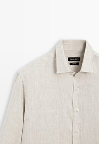 Light beige linen shirt with a collar, featuring a button-down front and a textured fabric, made by Massimo Dutti.