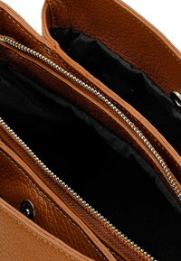 Borsa a tracolla in pelle marrone con texture, dotata di due scomparti con zip e fodera in tessuto nero. Presenta hardware in tonalità argento e cuciture a contrasto.