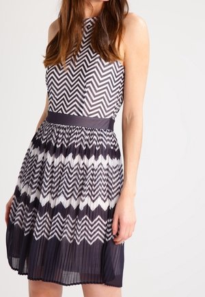 Robe à imprimé chevron bleu marine et blanc avec un corsage ajusté, une jupe plissée et une taille unie. Design sans manches, longueur genoux.