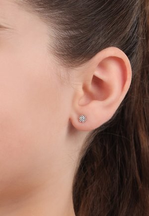 Boucles d'oreilles façon studs en argent avec six griffes en forme de pétales entourant un zircon cubique central. Taille petite, texture lisse et design minimaliste.