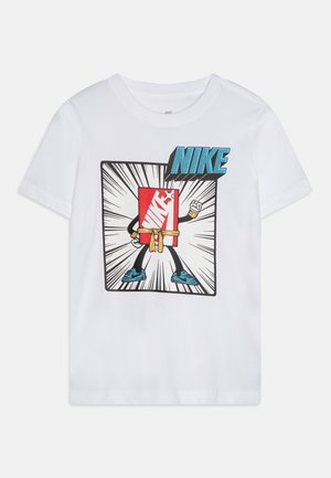 T-shirt en coton blanc présentant un graphisme d'un personnage de dessin animé avec un logo Nike rouge, des accents bleus et des chaussures noires dans un style bande dessinée.