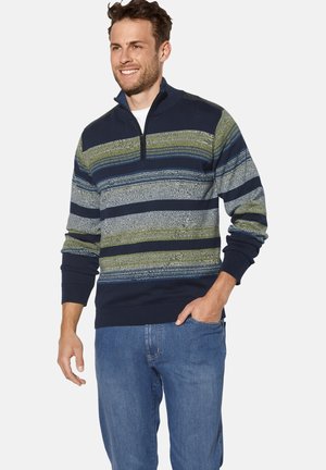 Marineblauer und grüner gestreifter Pullover mit halbem Reißverschluss am Kragen, strukturiertem Strickmaterial, enganliegenden Bündchen und einem gerippten Saum. Über Denim getragen.