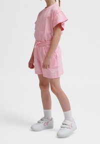 T-shirt en coton rose avec manches courtes à volants et un logo sur le devant, accompagné d'un short rose assorti avec une taille élastique et des poches latérales.