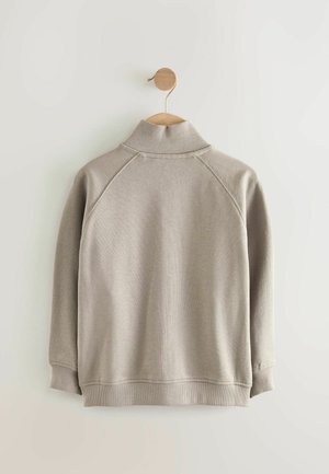 Hellgrauer Pullover mit hohem Kragen, gerippten Bündchen und Saum. Verfügt über Raglanärmel und eine glatte Strickstruktur.