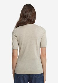 Beige kortærmet sweater med en glat tekstur, rund halsudsk�æring og ribbet kant. Stoffet virker let og tætsiddende.