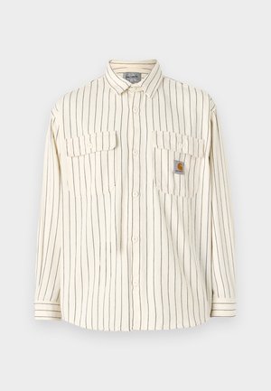 Cremefarvet skjorte med lodrette navy striber, to brystlommer og et mærketape. Lange ærmer med knapmanchetter.