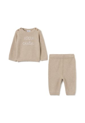 Ensemble beige en tricot pour tout-petits comprenant un haut à manches longues avec le texte "100% mignon" et un pantalon assorti avec une taille à côtes et des poignets.