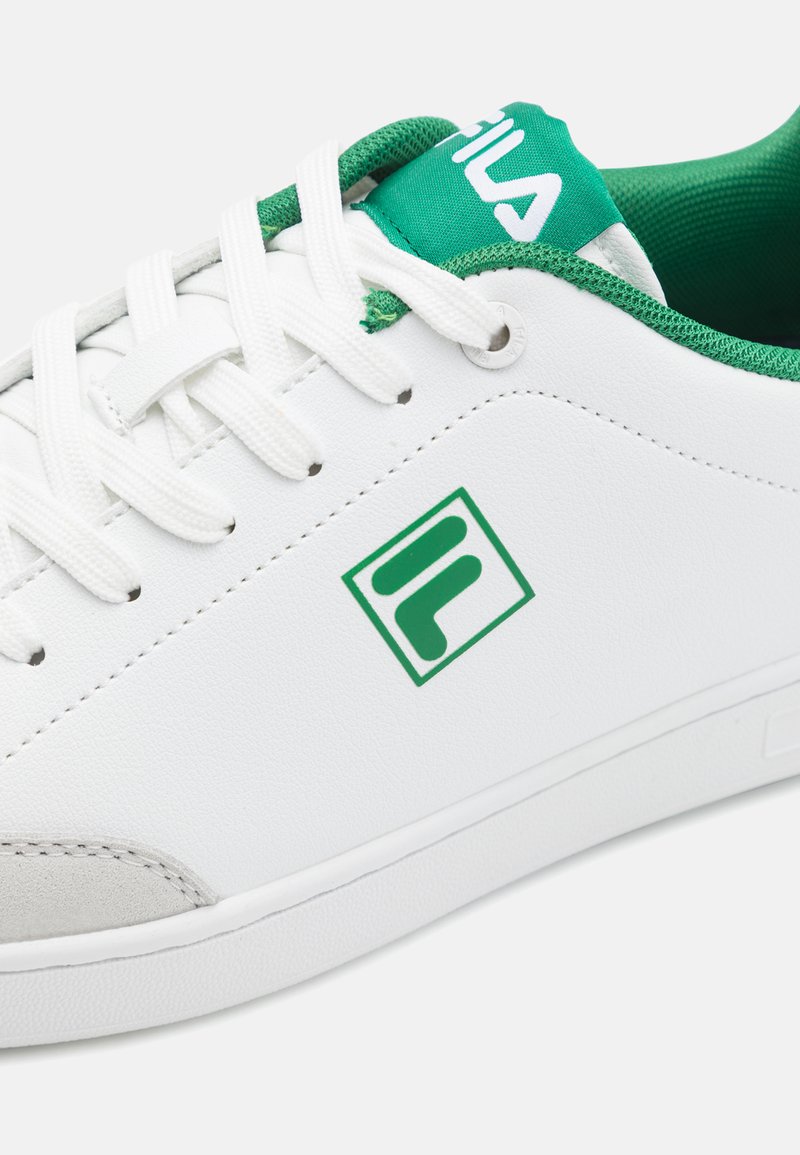 Baskets blanches avec des accents verts, fabriquées en matériau synthétique. Présentent une languette en relief, un col vert et un logo au niveau du milieu.