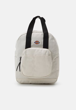 Kleine beige rugzak met zwarte handvatten, voorvak met rits en Dickies-logo aan de bovenkant voorkant.