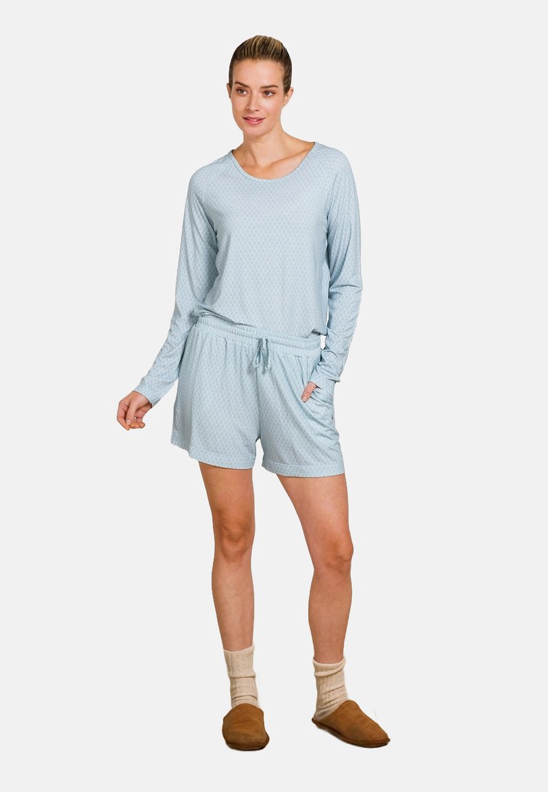 Lichtblauw, lange mouwen top met een ronde halslijn en gestructureerd patroon; gecombineerd met bijpassende shorts en bruine slippers.