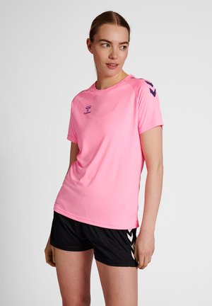 T-shirt de sport rose à manches courtes, col rond, avec un logo violet ; associé à un short noir avec des accents chevron blancs.