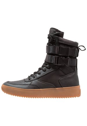 Baskets montantes en cuir noir avec panneaux en mesh, lacets à l'avant, deux sangles à boucle réglables et une semelle épaisse en gomme.