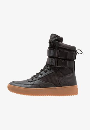 Baskets montantes en cuir noir avec panneaux en mesh, lacets à l'avant, deux sangles à boucle réglables et une semelle épaisse en gomme.