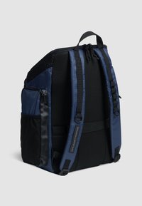 Rygsæk lavet af marineblåt stof, med et mesh bagpanel, justerbare stropper og en sidelomme med lynlås. Struktureret overflade og slankt design.